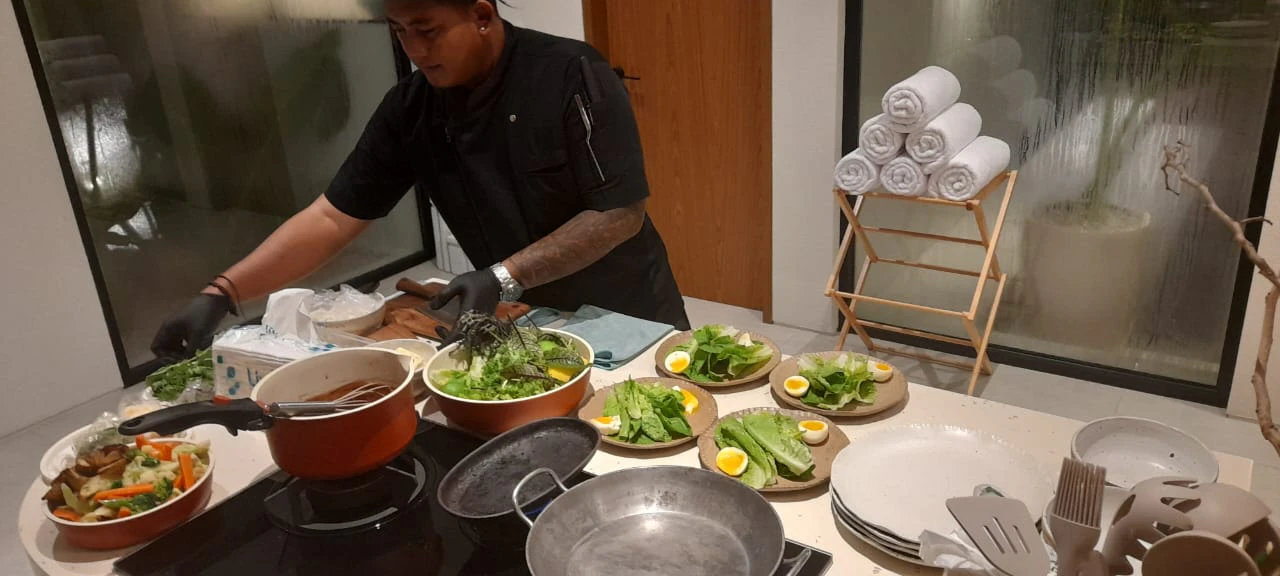 Chef Galung plating salads on a villa kitchen counter