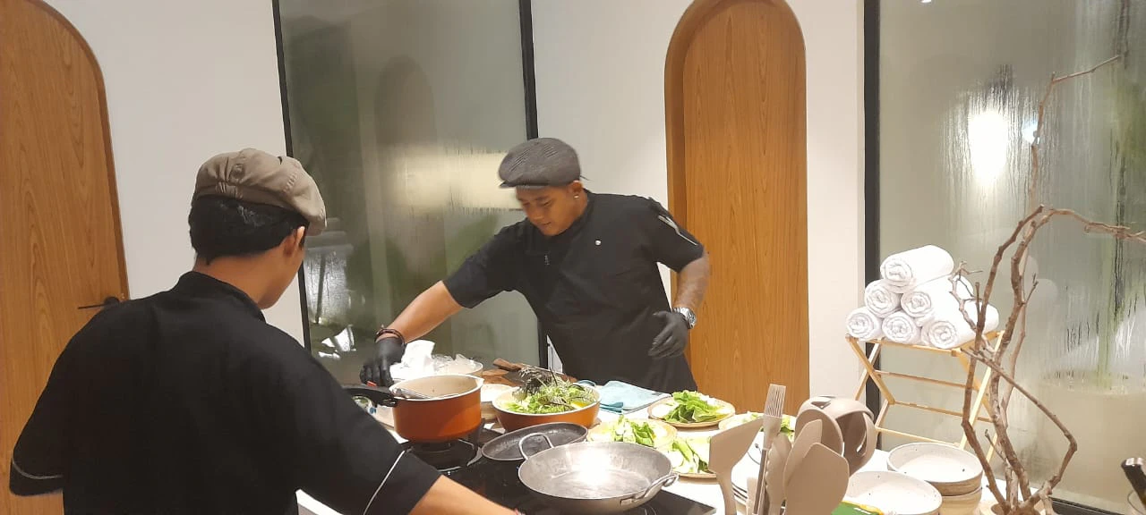 Chef Galung and an assistant preparing dishes side by side in a villa kitchen