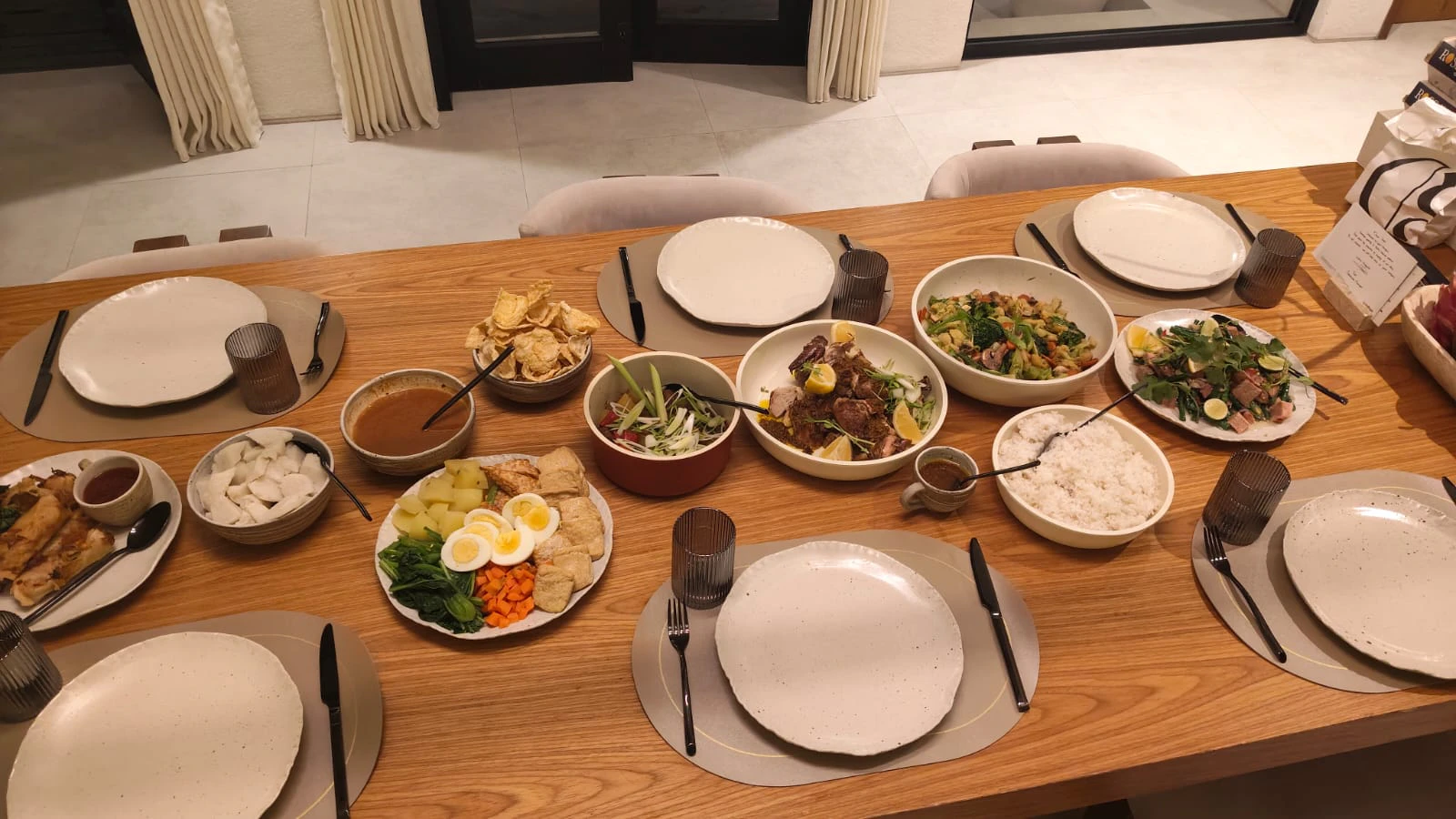 A family-style spread of rice, vegetables, meat and sambal along a long table