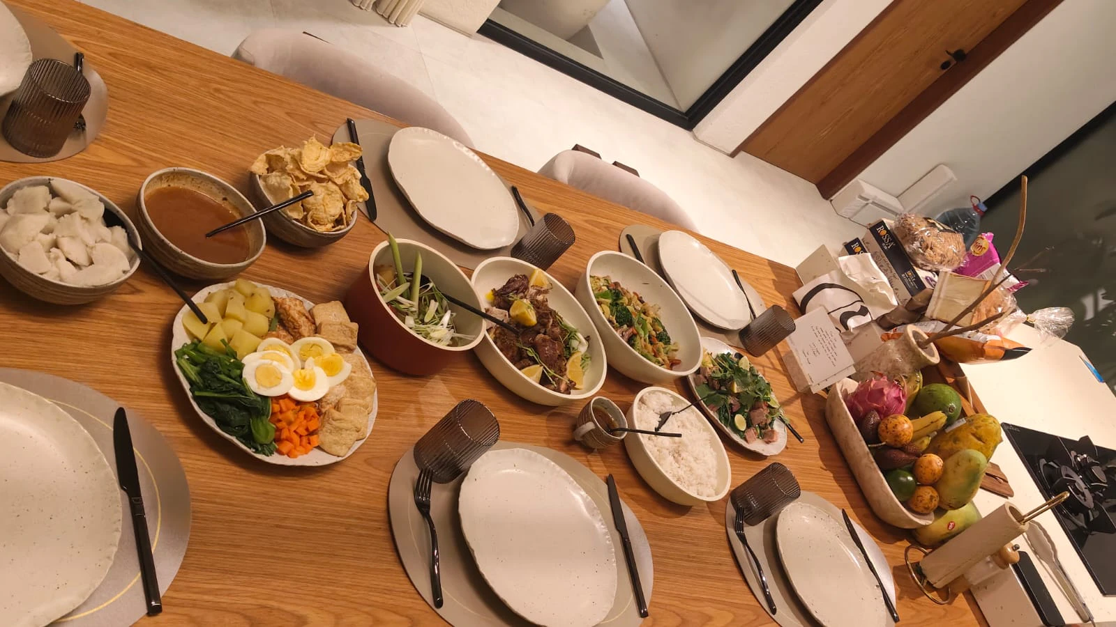 An Indonesian spread of rice, vegetables, eggs and crackers laid along a wooden table