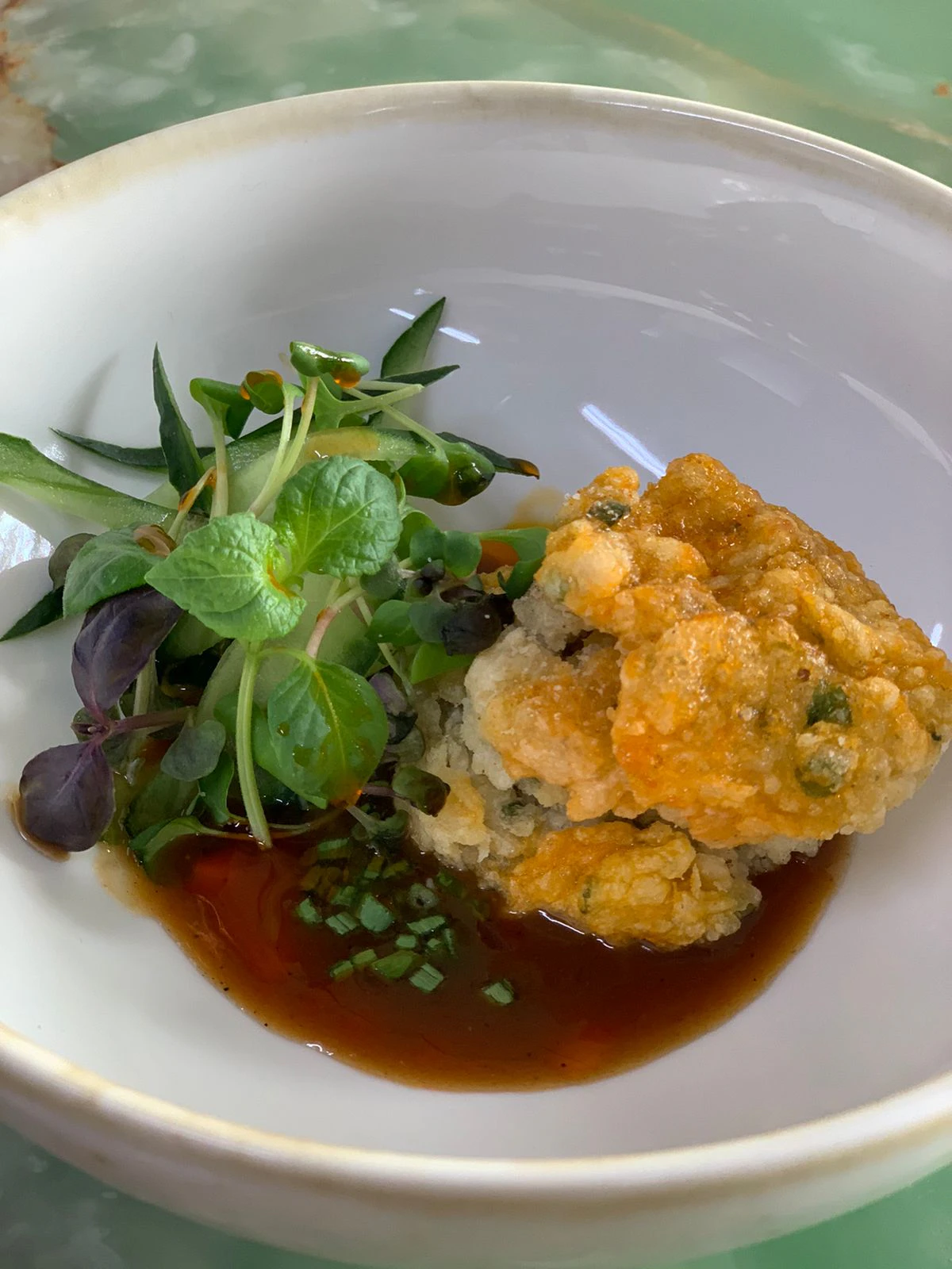 Crisp battered seafood in a white bowl with soy dressing and micro herbs
